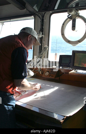 Navigator standing over charts working out the ships course Stock Photo