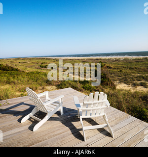 Two adirondack chairs on wooden deck overlooking beach at Bald Head Island North Carolina Stock Photo