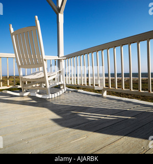 Rocking chair on porch with railing overlooking beach at Bald Head Island North Carolina Stock Photo