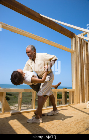 African American middle aged couple dancing in new home construction at beach Stock Photo