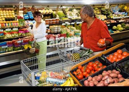 Middle aged African American woman pointing out produce in grocery store to middle aged man Stock Photo