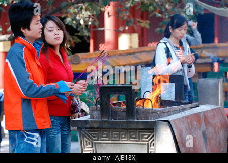 Young Buddhists lighting incense sticks at Yonghe Gong Temple Stock Photo