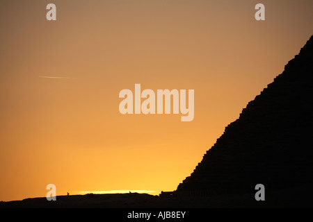 Pyramids of Khafre Chefren with stone blocks and small figures in sihouette in evening at sunset Giza Cairo Egypt Africa Stock Photo