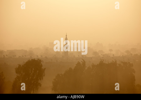 Trees houses and mosque minaret with early morning hazy mist sunlight Giza Cairo Egypt Africa Stock Photo