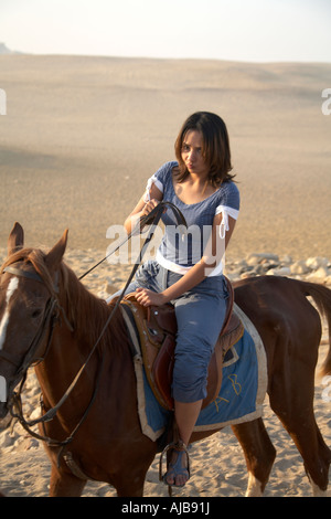 Local woman or girl riding horse in stony desert in early morning hazy sunlight Giza Cairo Egypt Africa Stock Photo