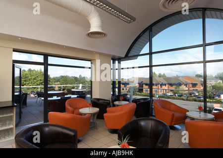 Seating coffee area in modern office building for staff with orange and black chairs and view through window Stock Photo