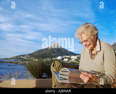 An Elderly Women Reading a Magazine with Lion's Head in the Background Stock Photo