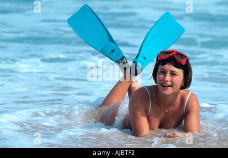 woman lying in ocean surf, wearing flippers and diving goggles Stock Photo