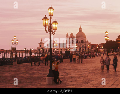 Couple embracing against lamp post on waterfront walkway near Piazza San Marco or St. Marks Square in Venice at sunset Stock Photo