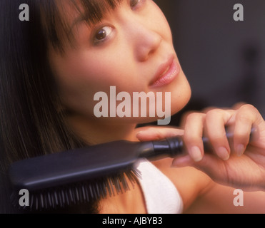 Close up of Asian woman brushing long black hair Stock Photo