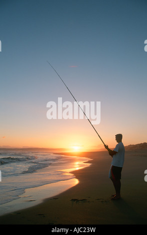 Silhouette of a Lone Fisherman Fishing at Sunset Stock Photo