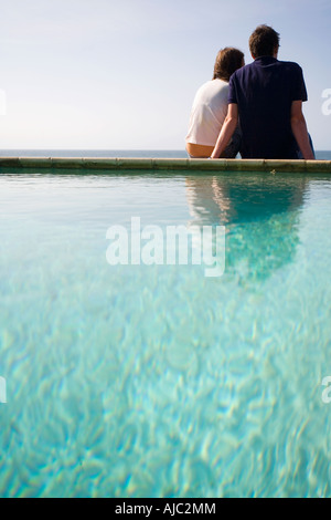 Couple Sitting on Edge of Swimming Pool Stock Photo