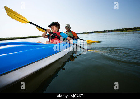 Low angle of African American middle aged man and woman paddling kayak Stock Photo