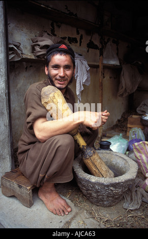 Afghan man pounding tobacco with a mortar and pestle Maidan a small Afghani community near Dir Pakistan Stock Photo