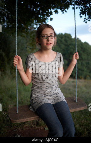 An eleven year old girl sits innocently on a holiday swing in Little Dewchurch Herefordshire England Stock Photo