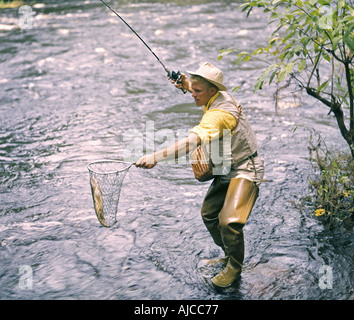 fisherman nets fish in stream Stock Photo