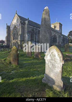 The All Saints Parish Church and ancient monolith standing stone at East Rudston on the Yorkshire Wolds, North Yorkshire, UK Stock Photo