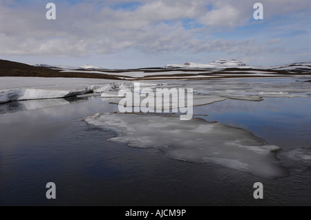 Spring melt in the Miohusaa river above the town of Egilstadir with a distant view of the Fjardarheidi mountains east Iceland Stock Photo