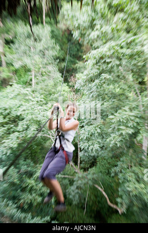 Woman high above the canopy on a zip line at The Gibbon Experience near Huay Xai on the Mekong river near the Laos Thai border Stock Photo