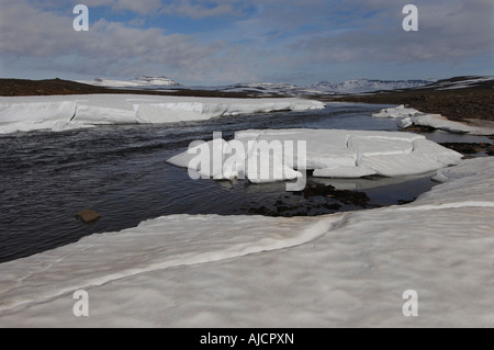 Spring melt in the Miohusaa river above the town of Egilstadir with a distant view of the Fjardarheidi mountains east Iceland Stock Photo