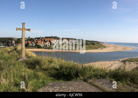 The coastal village of Alnmouth in Northumberland England as viewed from Church Hill with a carved Saxon cross in the foreground Stock Photo