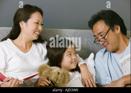 Mother and father relaxing in bed with daughter Stock Photo