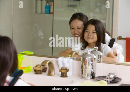 Mother and Daughter Looking at reflection in Bathroom mirror, focus on mirror Stock Photo
