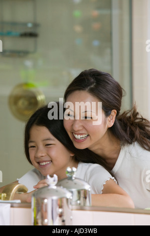 Mother and Daughter Looking at reflection in Bathroom mirror, focus on mirror Stock Photo