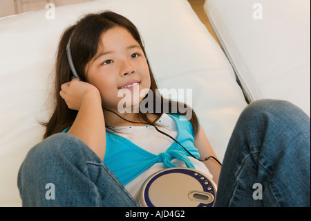 Girl lying in bed Listening to Music on CD Player, close up Stock Photo