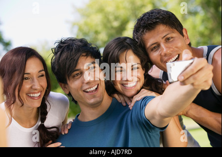 Young man using digital camera, photographing self with three friends. Stock Photo