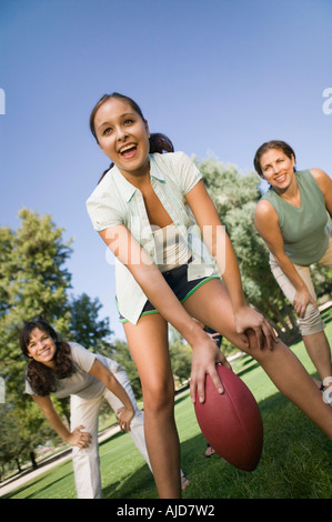 Three women playing football outdoors. Stock Photo