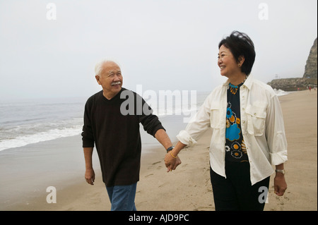 Mature couple holding hands, walking on beach Stock Photo