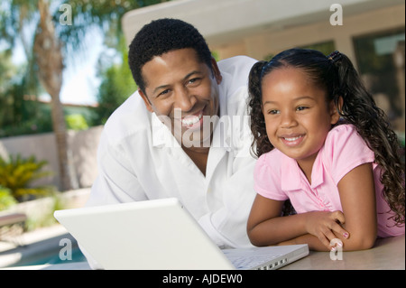 Father and Daughter Using Laptop on patio, portrait Stock Photo
