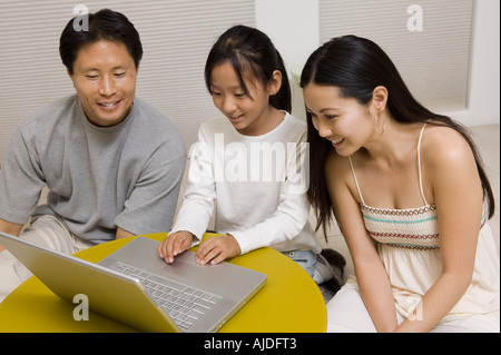 Daughter using laptop with mother and father in living room Stock Photo