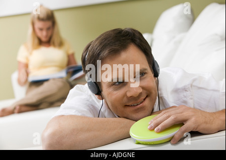 Man Listening to Music While Wife Reads Stock Photo