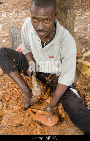 Craftsman makes traditional wooden mask Brikama craft market The Gambia Stock Photo