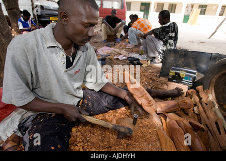 Craftsman makes traditional wooden mask Brikama craft market The Gambia Stock Photo