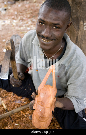 Craftsman makes traditional wooden mask Brikama craft market The Gambia Stock Photo