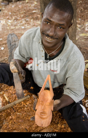 Craftsman makes traditional wooden mask Brikama craft market The Gambia Stock Photo