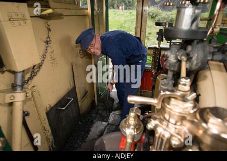 Drivers mate shovels coal into locomotive furnace Puffing Billy historic steam railway Melbourne Australia Stock Photo