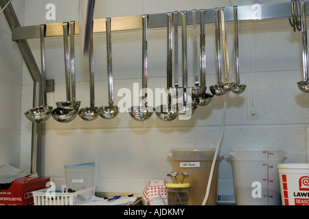 Various size ladles hanging from rack in school kitchen