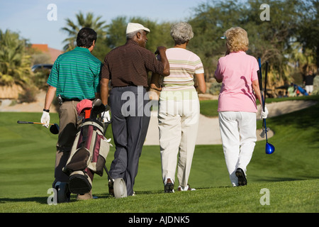 Group of senior golfers walking on golf course, back view Stock Photo