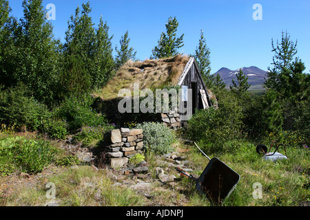 A mountain cabin in disrepair surrounded by growth and trees Stock Photo