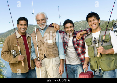 Middle-aged man with three sons holding fishing rods, smiling, (portrait) Stock Photo