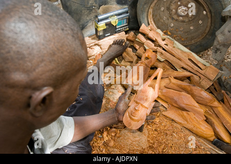 Craftsman makes traditional wooden mask Brikama craft market The Gambia Stock Photo