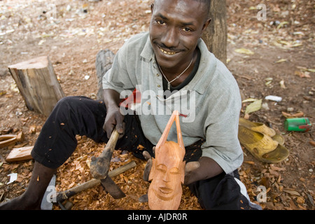 Craftsman makes traditional wooden mask Brikama craft market The Gambia Stock Photo