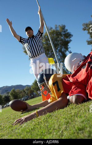 Referee signalling touchdown over football player tackled in end zone Stock Photo