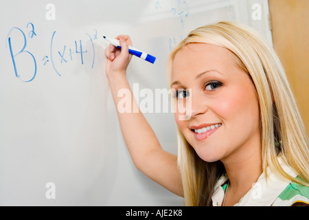 Female student writing equation on whiteboard, (portrait) Stock Photo