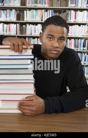 Male student with stack of books at library Stock Photo - Alamy