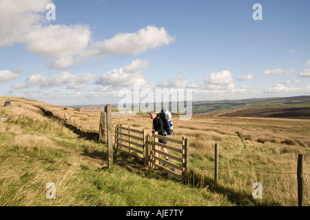 WEST YORKSHIRE England UK October Young man opening  gate carrying tent and ground sheet on Pennine Way on Wessenden Head Moor Stock Photo